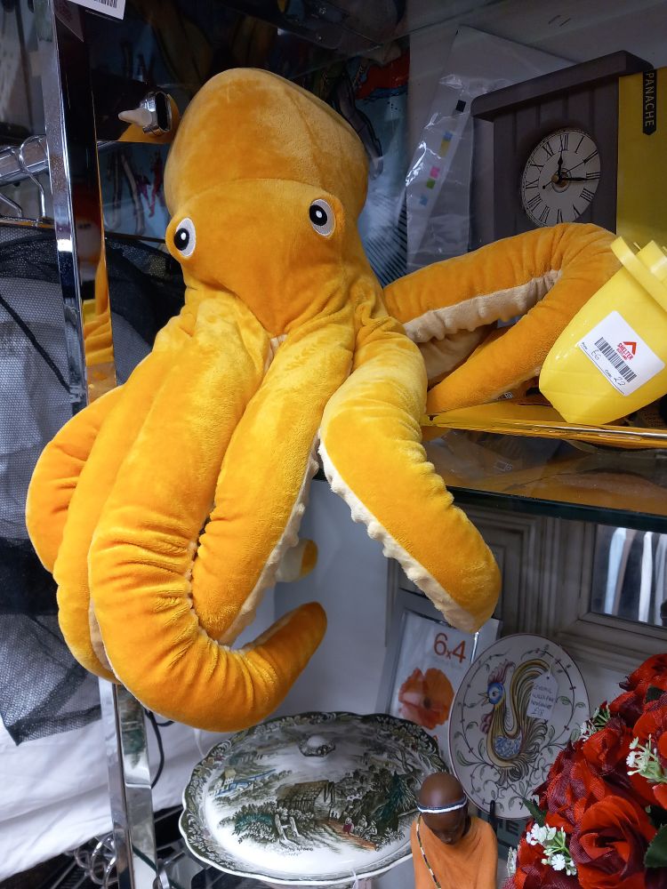 Yellow toy octopus on a shelf in a shop.