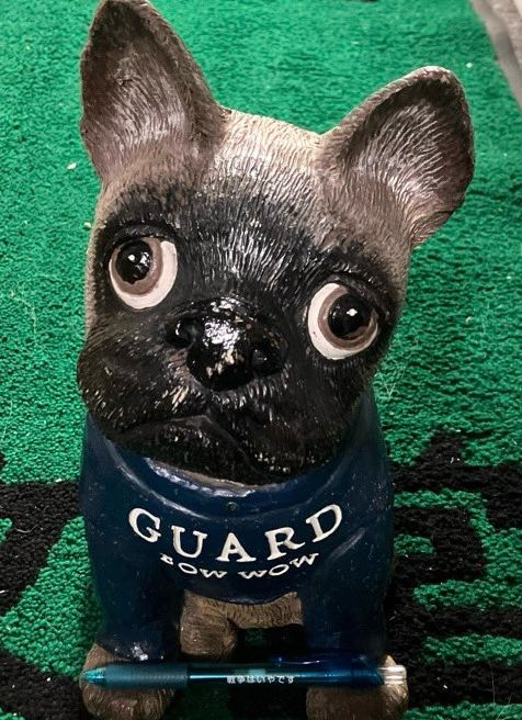 店頭でお客さまをお迎えしている犬(の置き物)です。その足元に、楽文堂オリジナルの「いやです」ボールペンを置いてみました。