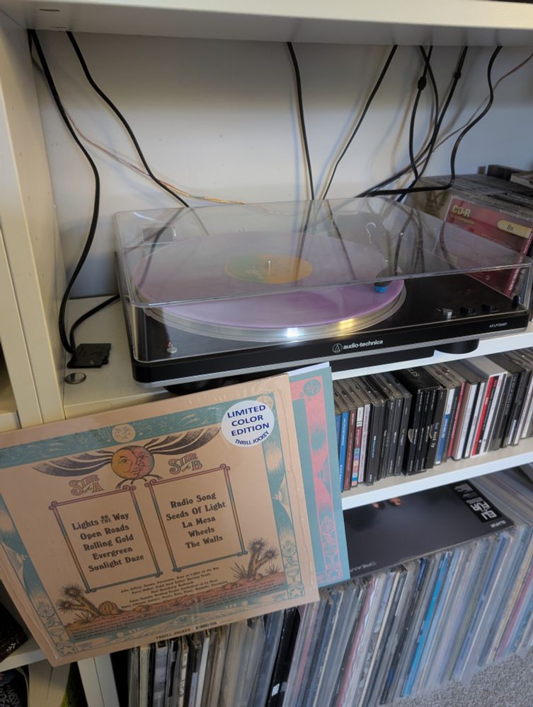 Back cover of Rose City Band's latest album and a record player playing the pink vinyl album.