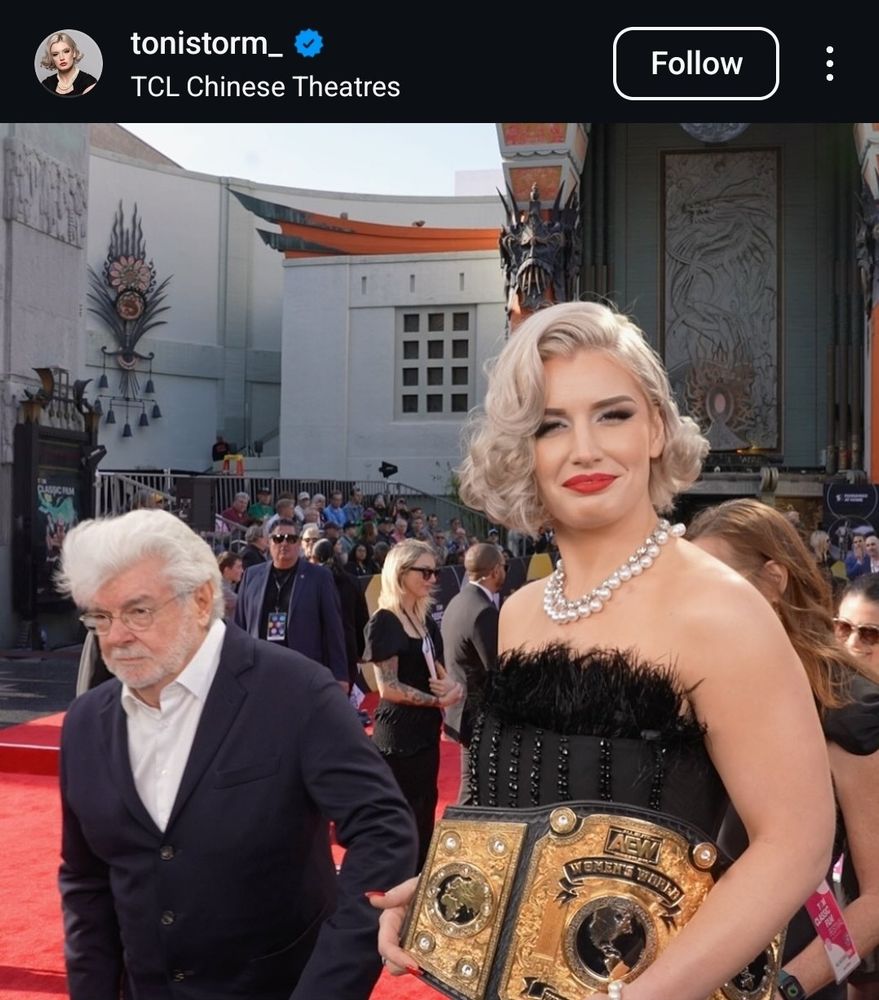 Toni Storm at the Chinese Theaters posing for the camera, with George Lucas grimacing past in the near background like bigfoot