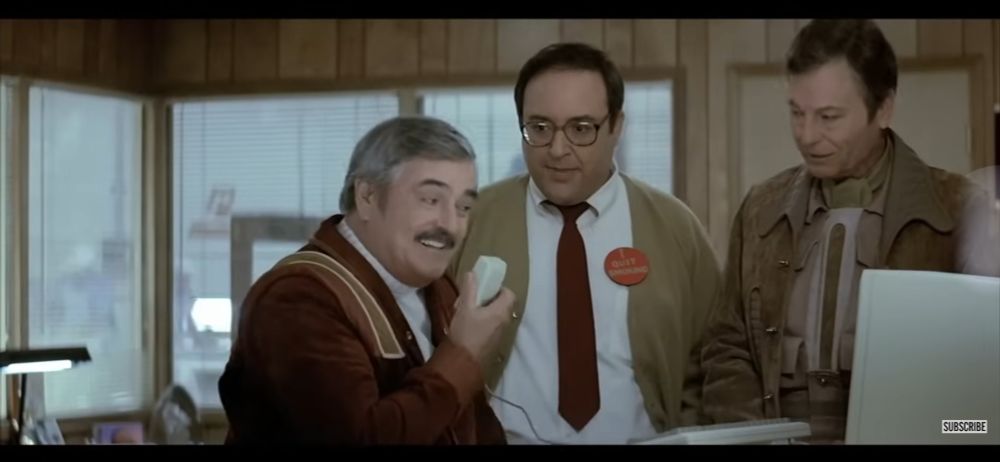Jimmy Dohan as Scotty and Deforest Kelly as Bones, with Dr Nichols between them from 1986. Dr Nichols is wearing an I quit smoking button. Scotty is talking into a computer mouse, smiling. Dr Nichols is looking at Scotty.