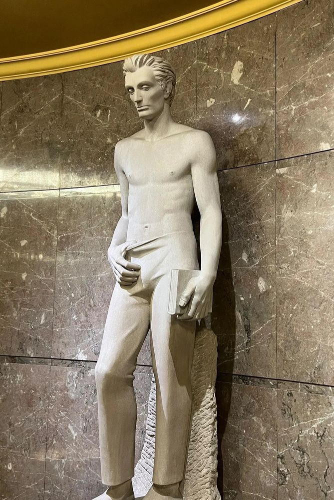 Statue of Babe Lincoln, with a twilight physique, shirtless, leaning against the wall with one leg up. He's holding a book on one hand and has his other hand hanging off his pants by his thumb, pulling the fabric down a little, teasing at his fun little play area before you get to the utilities and equipment. If Calvin Kline or Abercrombie or whatever did statues in their stores, they'd look like this.
