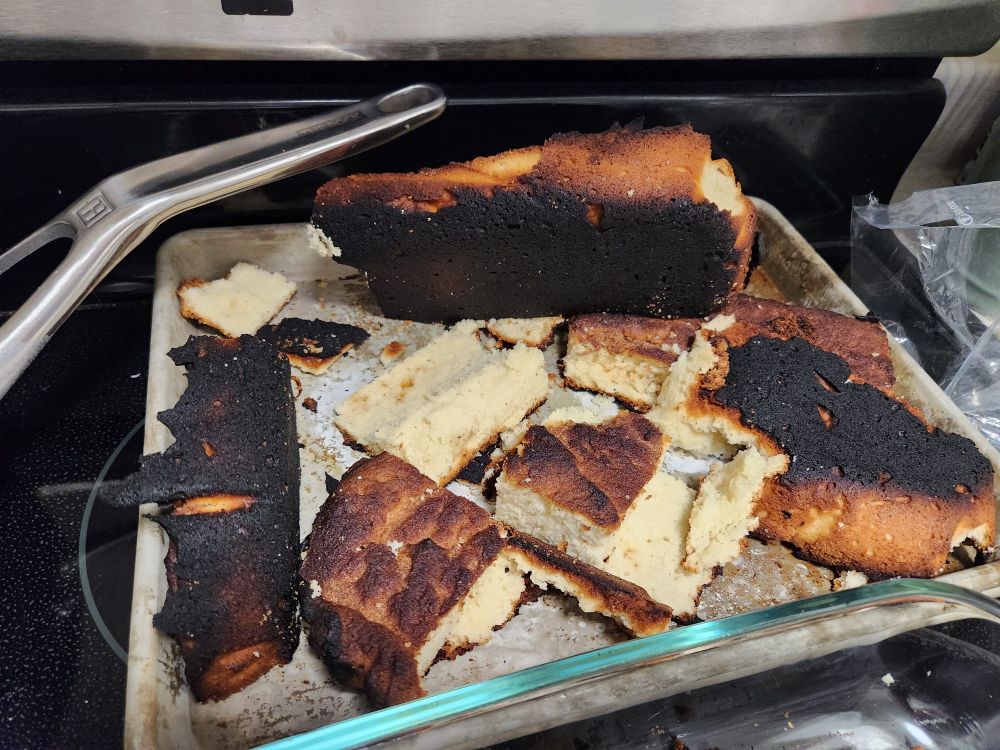 Burned cake cut up on a pan. 