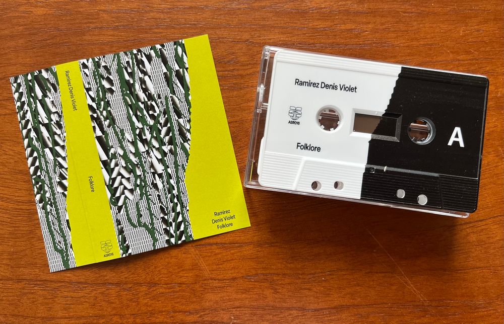Pack shot of the cassette edition of ‘Folklore’ by Ramirez, aka French synthesist Denis Violet: J-card (a digital graphic design in black, white and dark green on a lime green background); cassette shell (left half is white, right half is black)