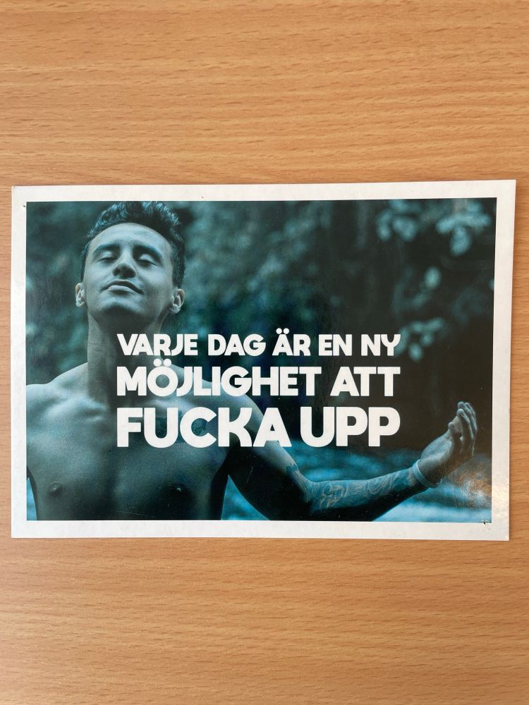 Bild på ett reklamvykort med texten ”varje dag är en ny möjlighet att fucka upp” med en bild på en man med armarna utsträckta och ett harmoniskt ansiktsuttryck 