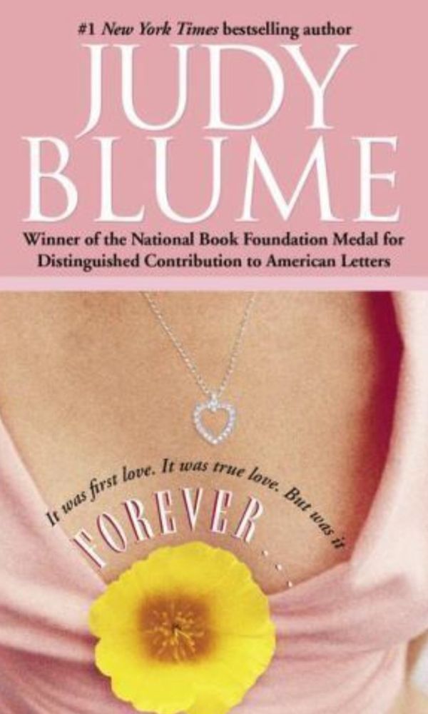 The words Judy Blume on white lettering. Photo of a heart shaped necklace dangling on a white female's cleavage, dressed in a pink blouse and a large yellow flower under thr words Forever