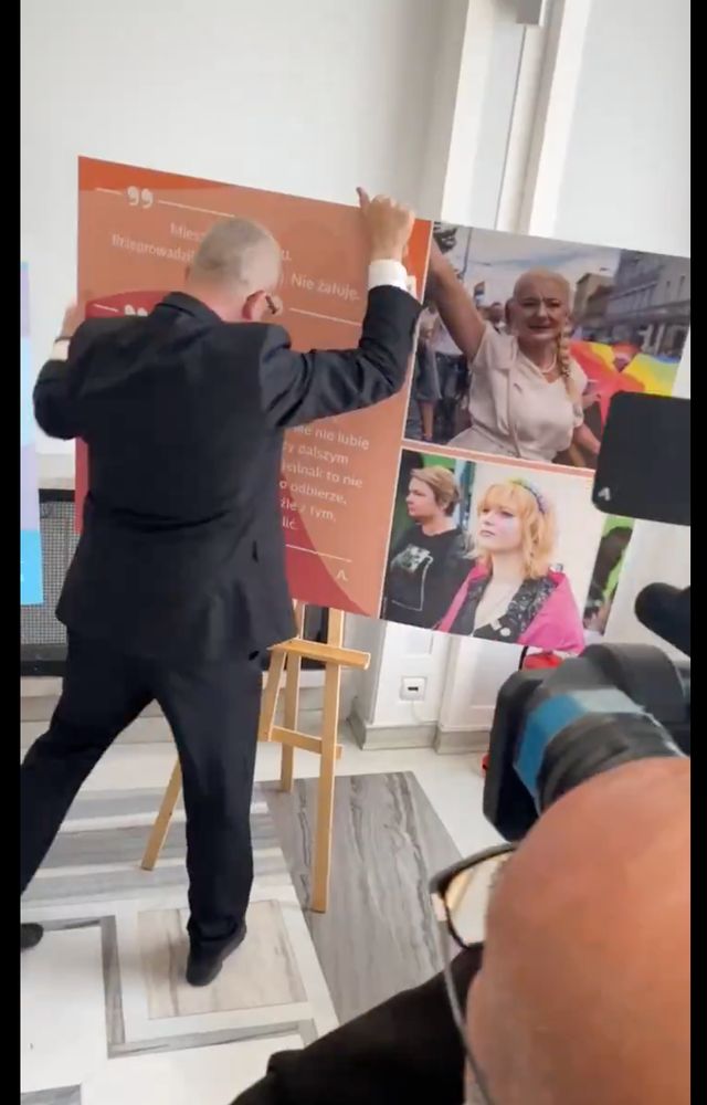 Person im Anzug hebt eine Ausstellungstafel hoch.