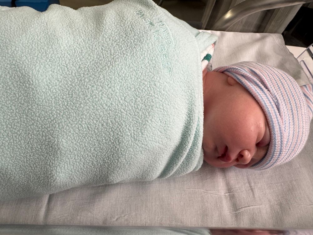 Arguably the cutest newborn baby girl in the world, soundly sleeping on her side in a swaddle.