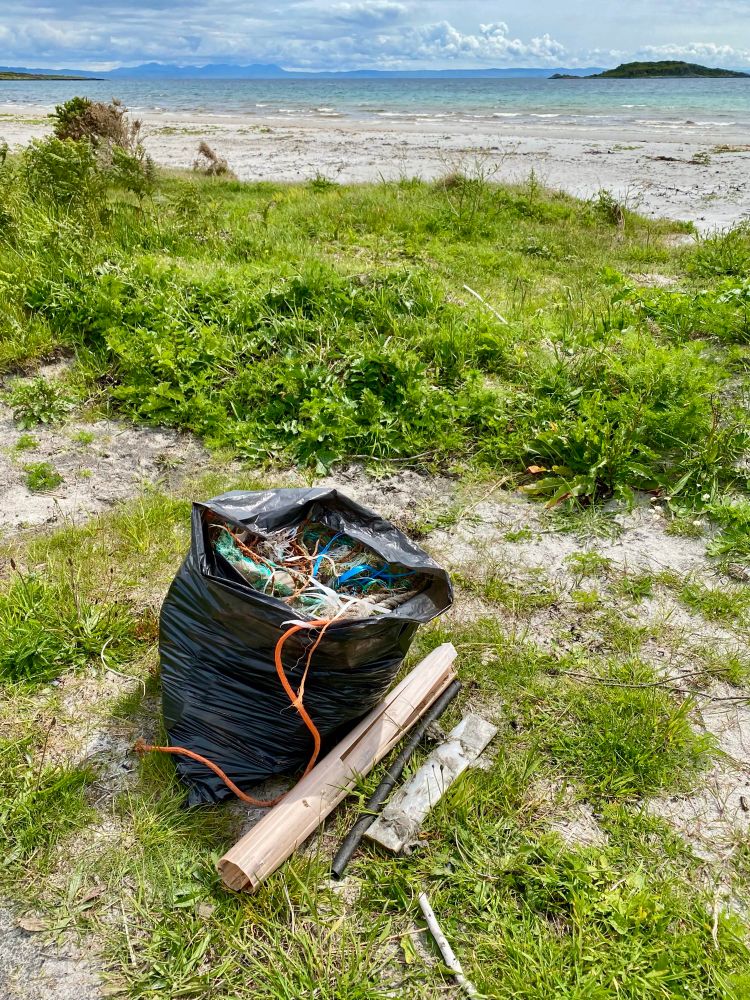 Refuse sack full of marine plastic, mostly fishing industry waste on a beautiful Isle of Jura beach looking out to the sea