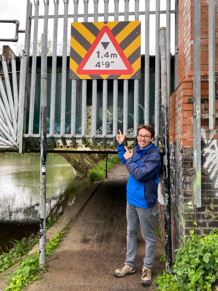 Standing in front of a low bridge sign marked 1.4m 4’9”