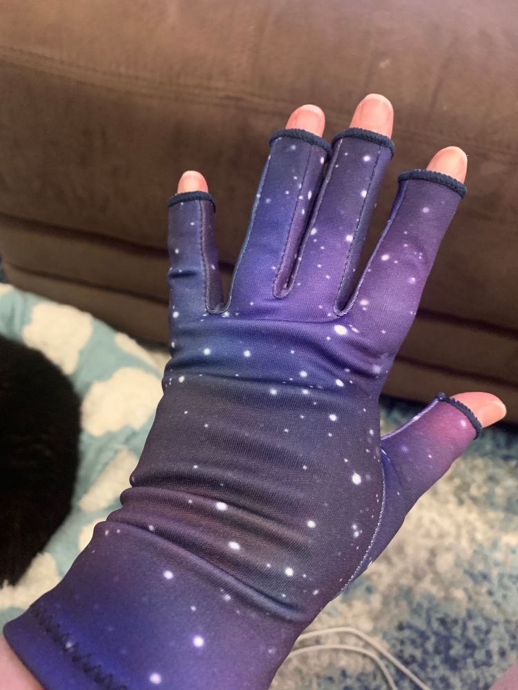 A picture of my hand covered in a fingerless compression glove with a purple galaxy print.