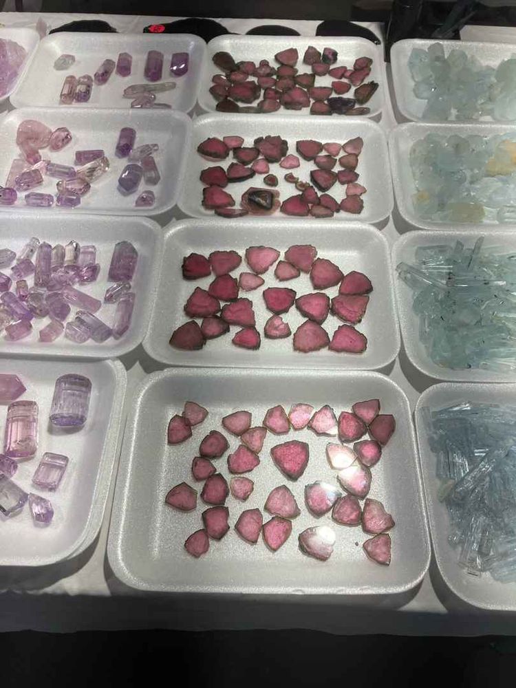 white trays of carved gemstones. the most centered are trays of reddish pink translucent rocks with darker, brownish edges. like slices of meat chunks