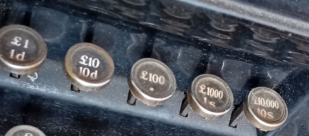 5 Round keys on old typewriter, labeled successively: £1/1d; £19/10d; £100/.; £1000/1s; £10,000/10s.
Looking rather like an old-style cash register.
