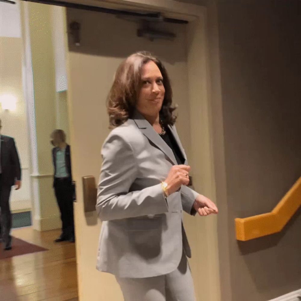 a woman in a suit stands in a hallway