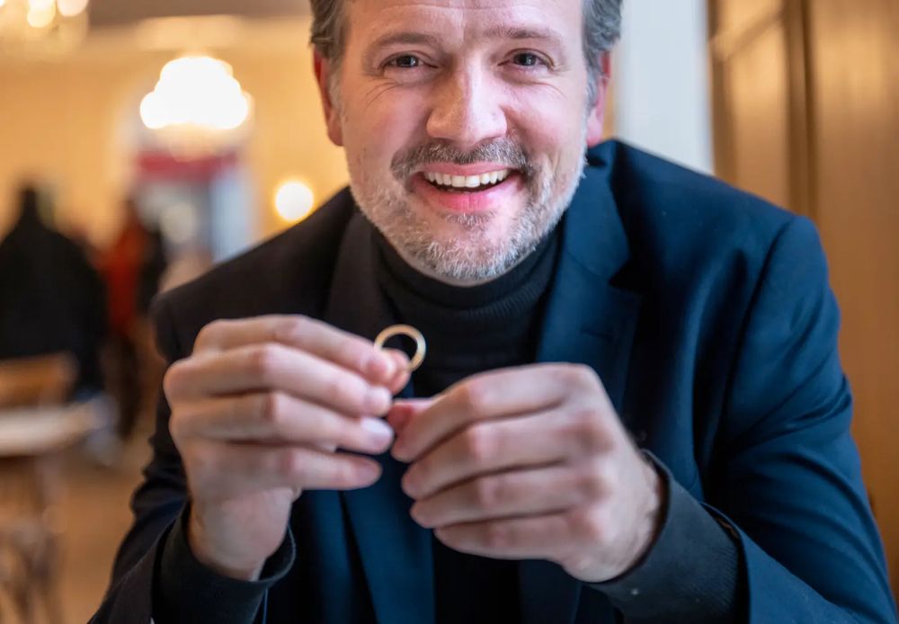 Dag Inge Ulstein smiler mens han ser inn i kameraet og holder gifteringen sin i den ene hånda 