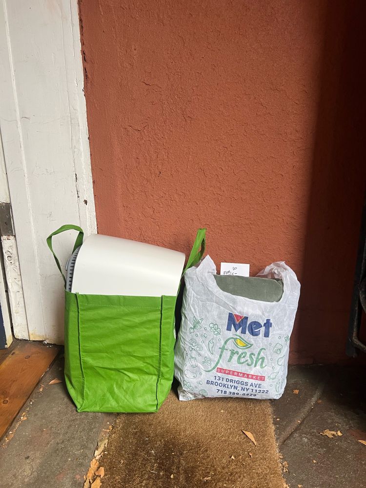 Photo of two grocery bags, filled with goods and a note. 