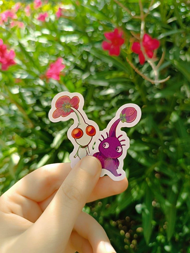 A photo of 2 pikmin stickers (white pikmin, purple pikmin) designed by me. 