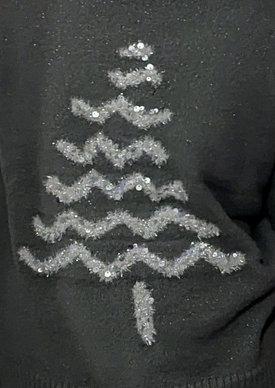 Close up of Christmas jumper. Grey cotton with silver glittery tinsel in shape of a tree