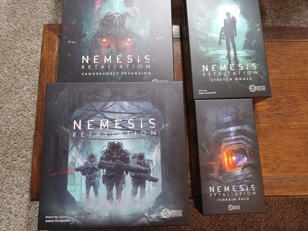 several board game boxes for the sci-fi horror board game nemesis retaliation.