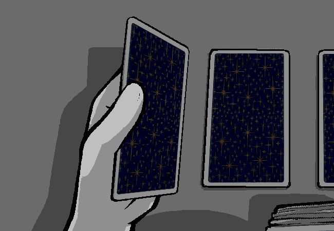 A mysterious induvidual is doing a tarot reading, placing three cards backside-up in a row, before presumably flipping them to reveal the cards.