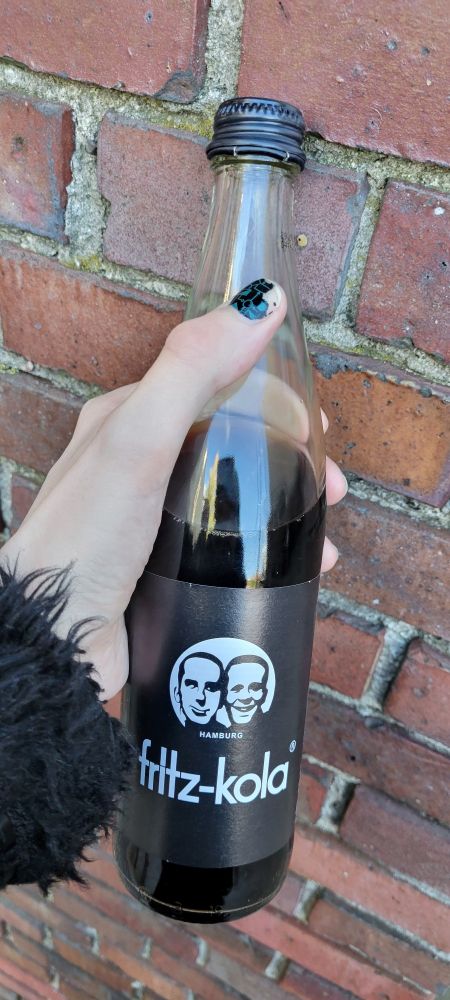My hand holding a 500ml bottle of Fritz Cola, with a screw top lid.