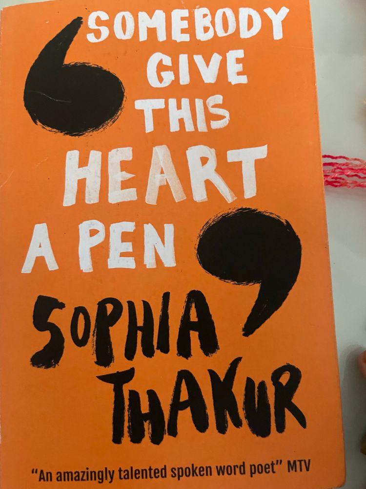 Orange Book cover , 

SOMEBODY GIVE THIS
HEART
A PEN (all is white text)
SOPHIA THAKUR (black text)
"An amazingly talented spoken word poet" MTV