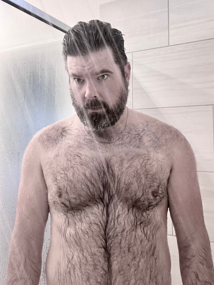 A shirtless man in a shower 