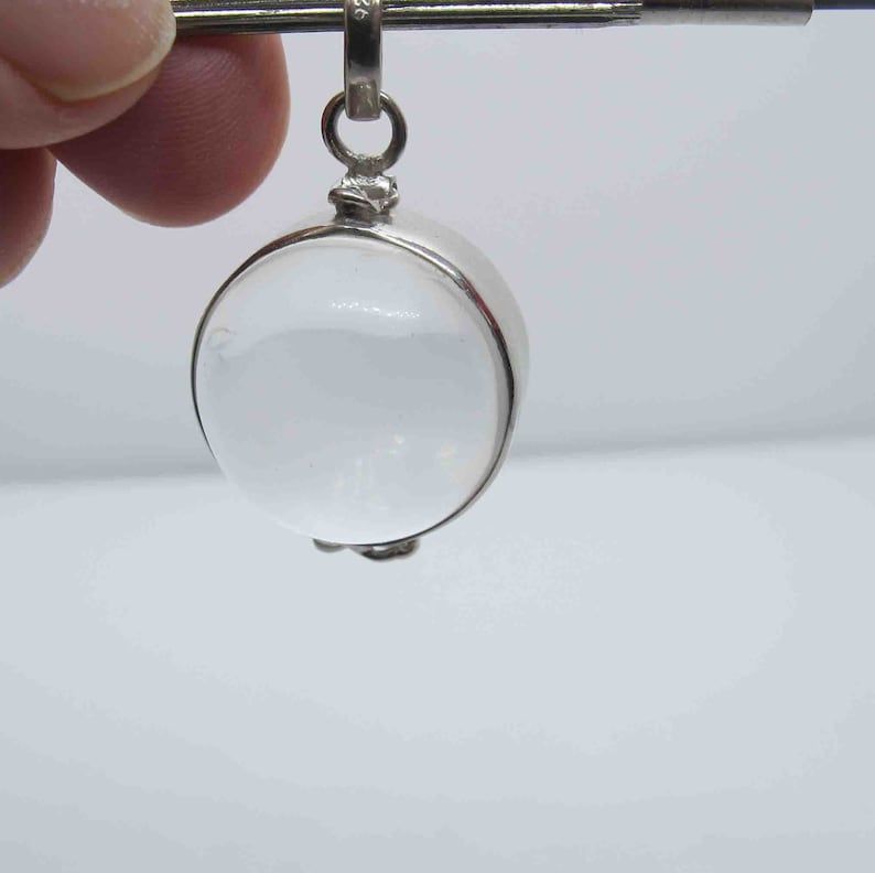A singular pool of light bead hanging on a silver rod