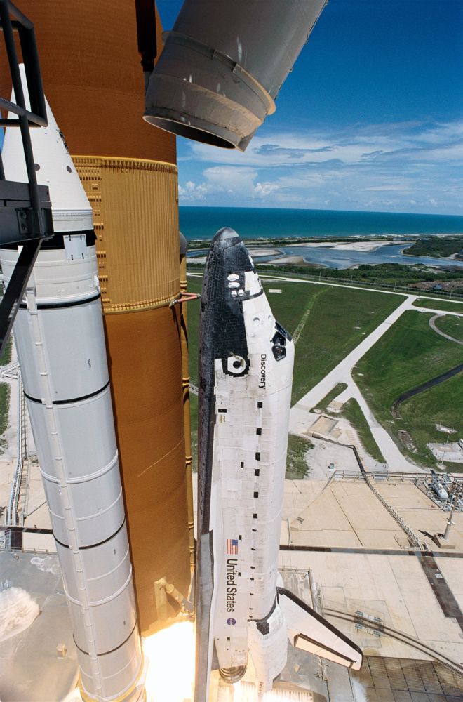 Impressive side-on closeup view of STS-121 launch, just after liftoff, with ocean and cape view in background.
