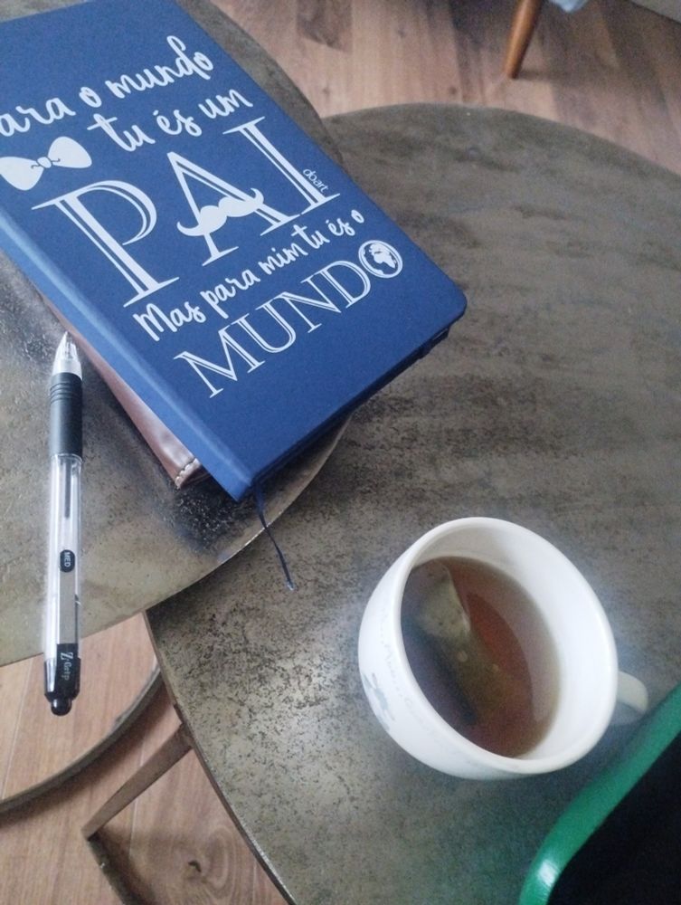 A notebook, pen and cup of peppermint tea on a small table