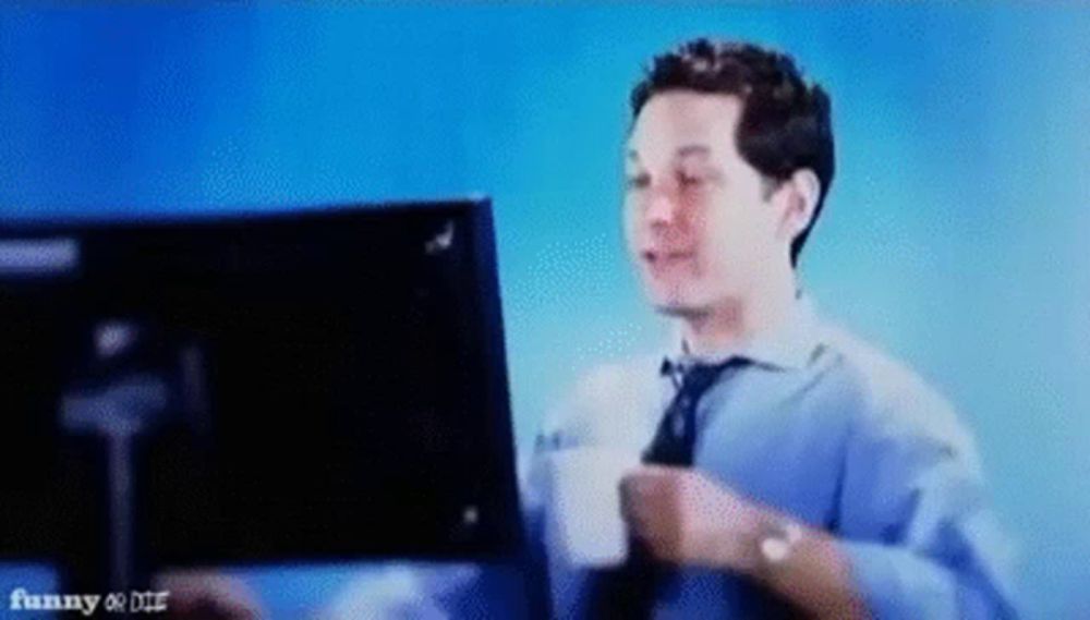 a man is holding a cup of coffee in front of a computer screen .