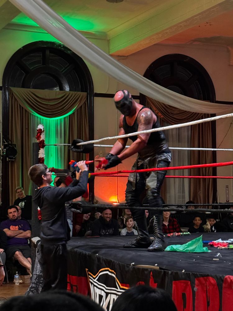 Small boy reaching up to receive a few toys from the wrestler krule inside the ring at blitzkrieg 