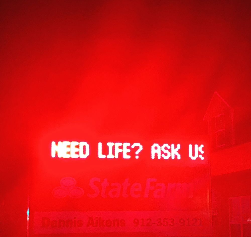 In neon red lights late at night;
“NEED LIFE? ASK US”