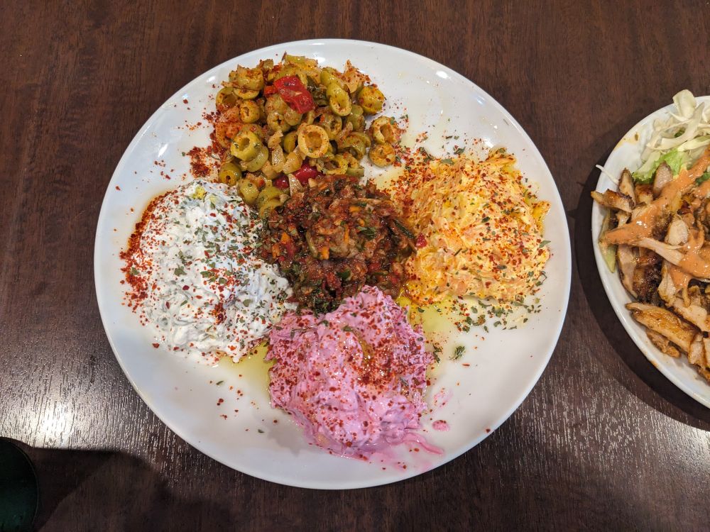 色とりどりの前菜5種が白い皿に盛られたトルコ料理の盛り合わせ。ヨーグルト、ビーツ、にんじん、オリーブ、トマトのディップに香辛料がかかっている。