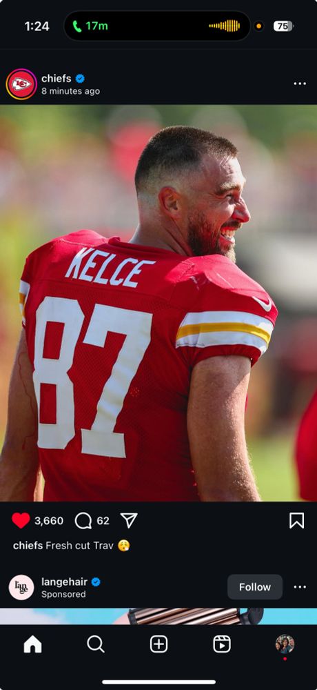 Photo of Travis kelce from behind wearing a red 87 jersey with a short haircut. 