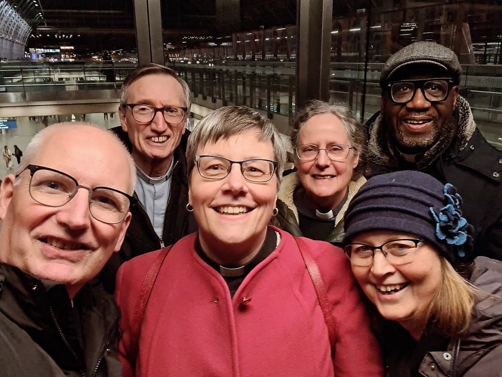 Lift selfie at St Pancras station. Three men, three women. Five white people, one black man. Three visible clerical collars. 
