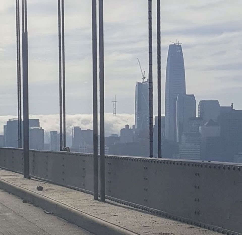 View from Bay Bridge in SF looking through high rise buildings at the Sutro Tower peeking out above the fog.