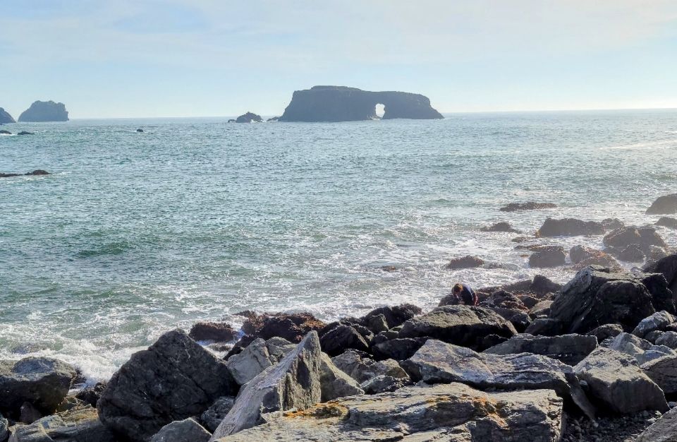 Standing on the rocky coast of Northern California looking out into the Pacific Ocean seeing a rock formation with a door like archway.