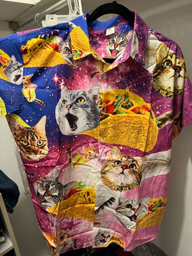 a short sleeve button down hawaiian shirt featuring numerous cat heads on taco and burrito bodies on a blue and purple starry background