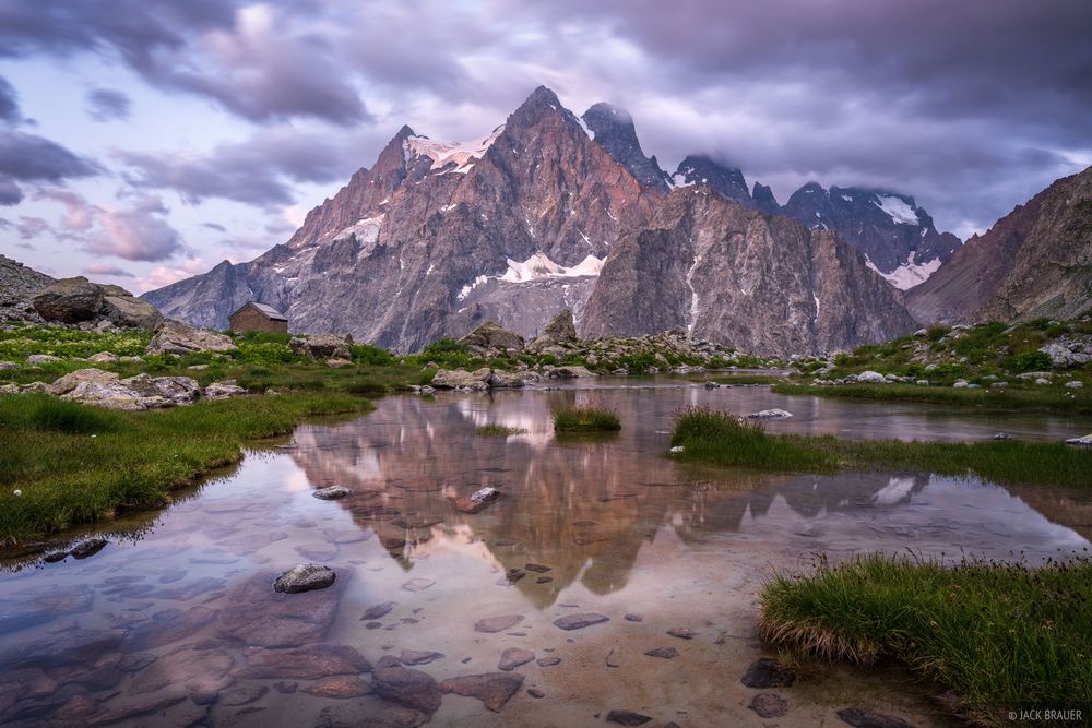 Mont Pelvoux (3,946 m / 12,946 ft) reflects in a creek at sunrise. The historic Refuge Tucket is visible to the left. Parc National des Écrins, France.