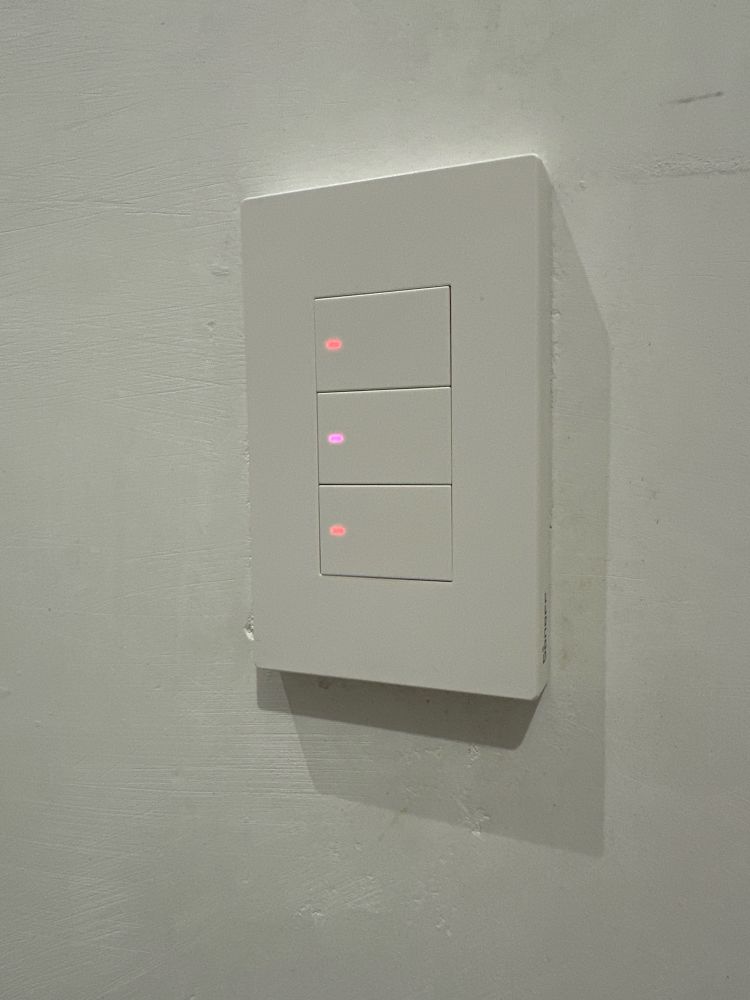 Sonoff 3 gang white smart switch. This is the US version (120w).

Each button has a small LED dot on the left side that indicates the state of the toggle:
- No light means light is turned off.
- Red color means the light is turned on.
The middle button’s LED shows blue if the light is turned off, and it turns purple-ish if the light is turned on.