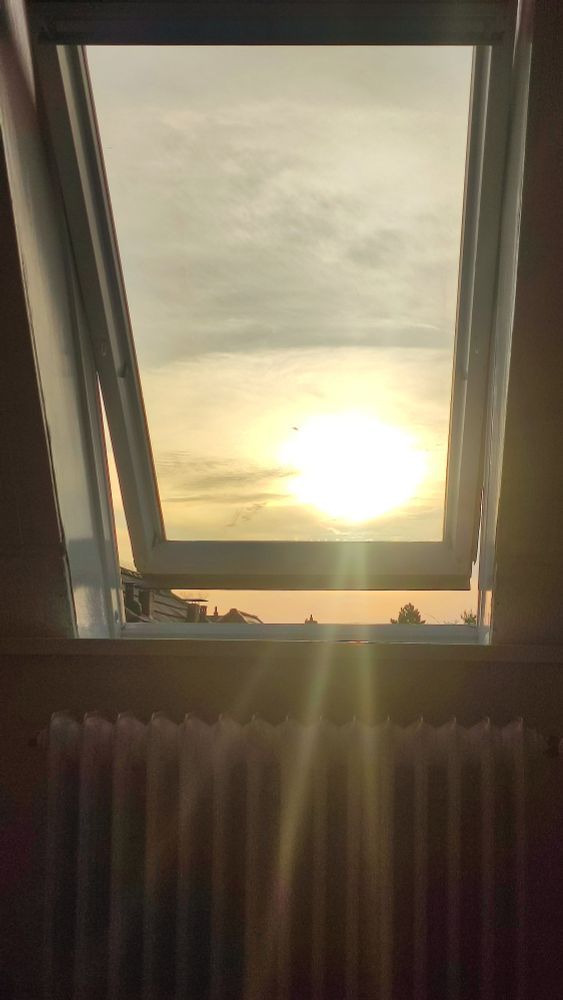 Foto eines Sonnenuntergangs, der durch ein Dachfenster scheint