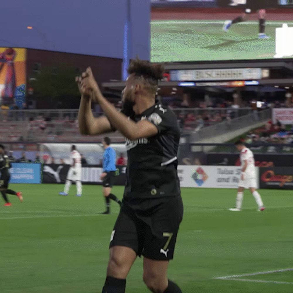 a soccer player with the number 7 on his shorts stands on the field