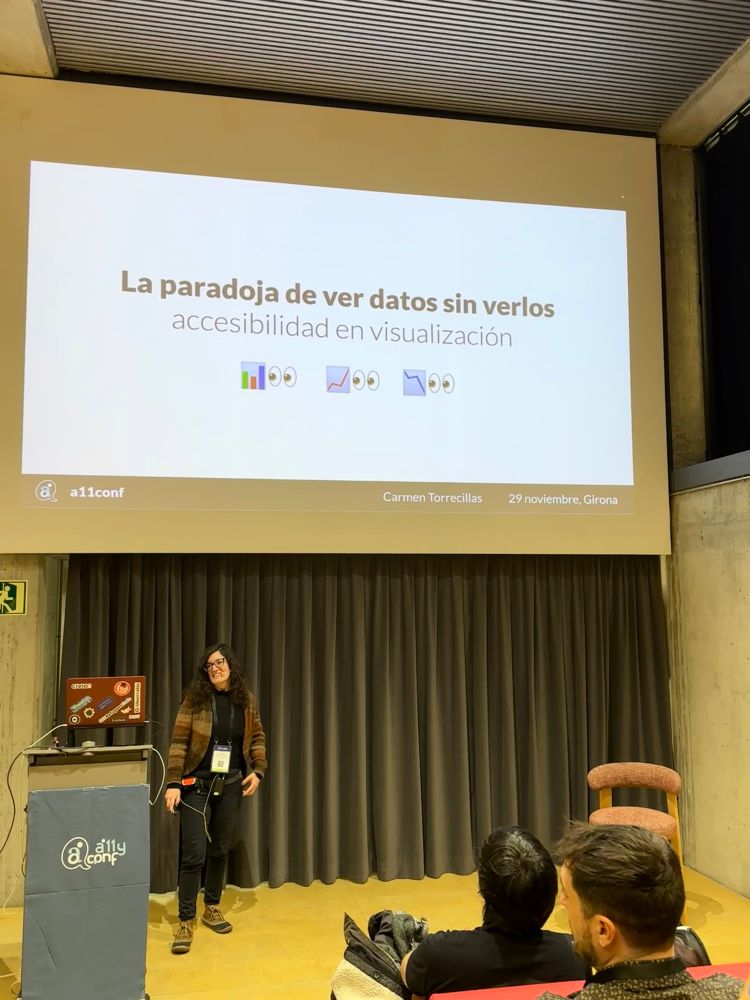 Carmen Torrecillas en el escenario del auditorio de la a11yConf 2025 en Gerona hablando de visualizacion de datos accesible delante de la audiencia