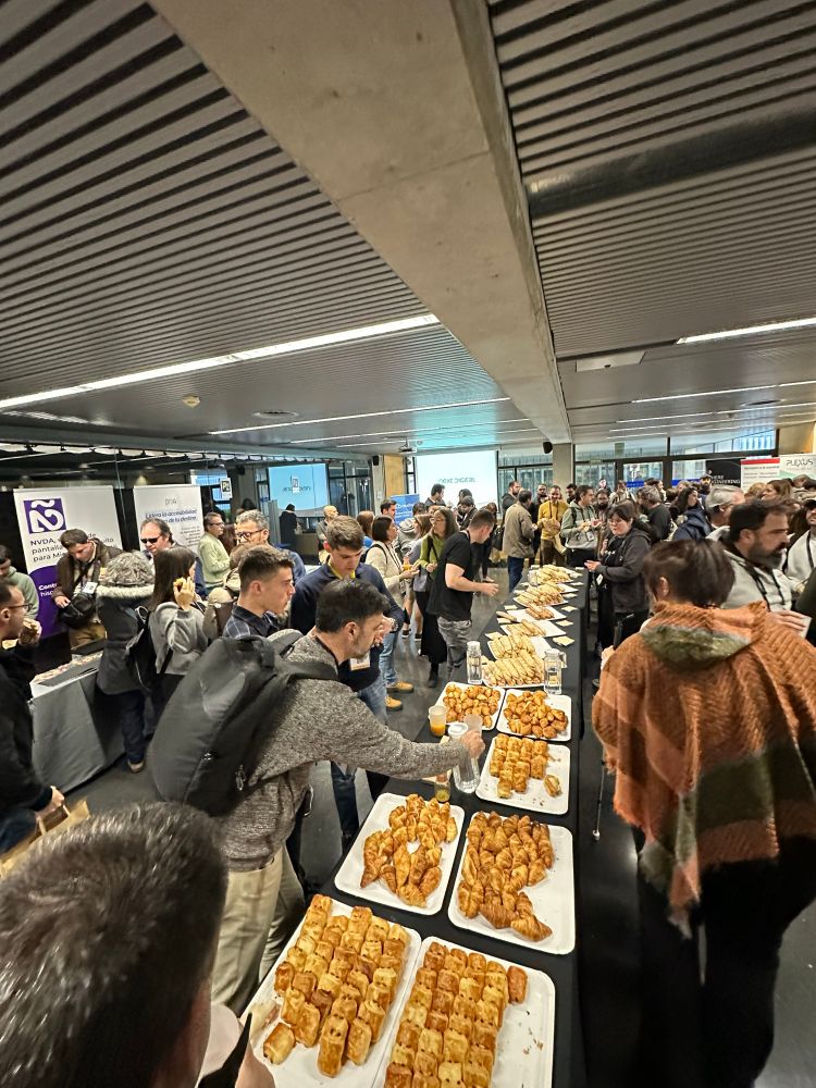 Assistents fent el coffee break amb entrepans i croissants, mentre fan networking