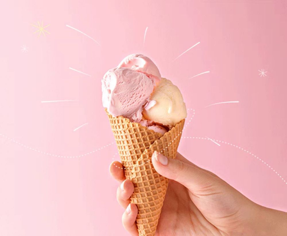 a hand holding an ice cream cone with two different flavors