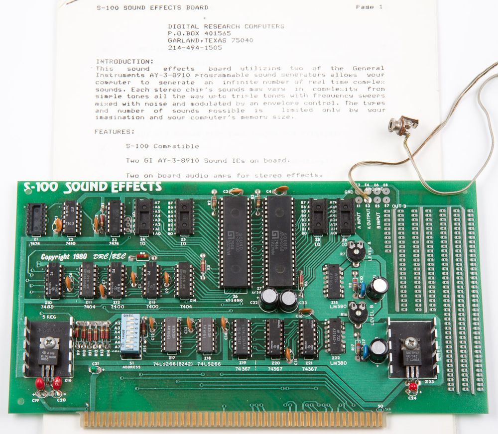 a populated S-100 sound-effects board on top of a stapled manual. A headphone jack dangles from a wire soldered to the upper right of the board. credit to deramp.com for the image.
