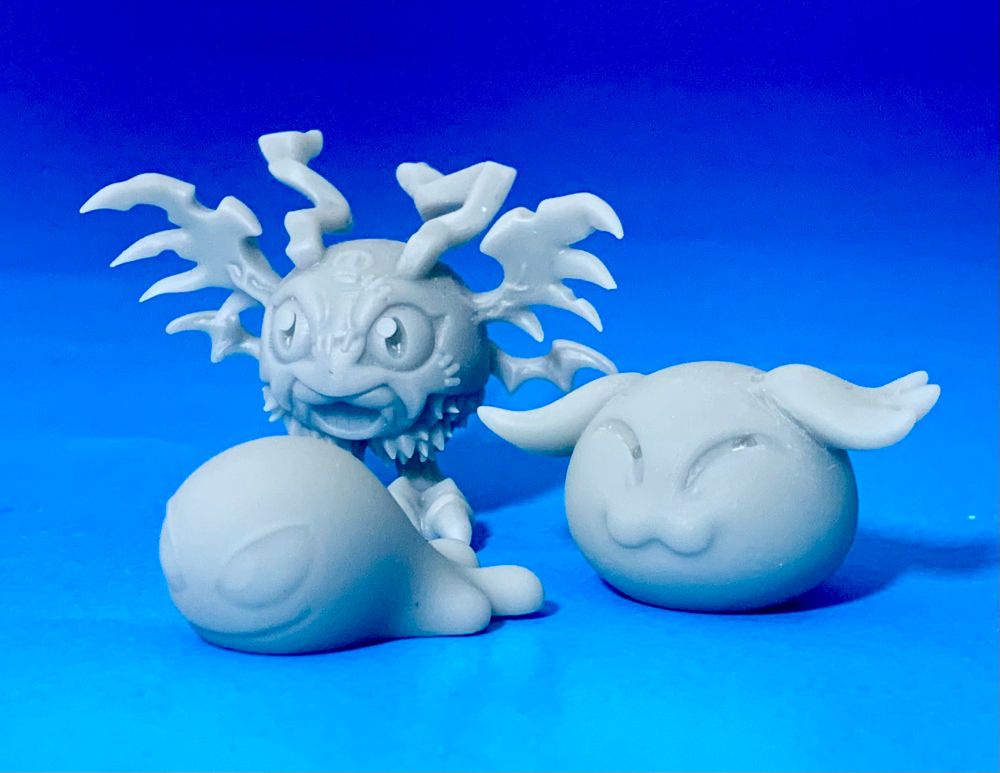 The Digimon Demidevimon, standing in front of a blue gradient backdrop with its two baby forms: Pagumon and Zurumon. All 3 are unpainted and grey. 
