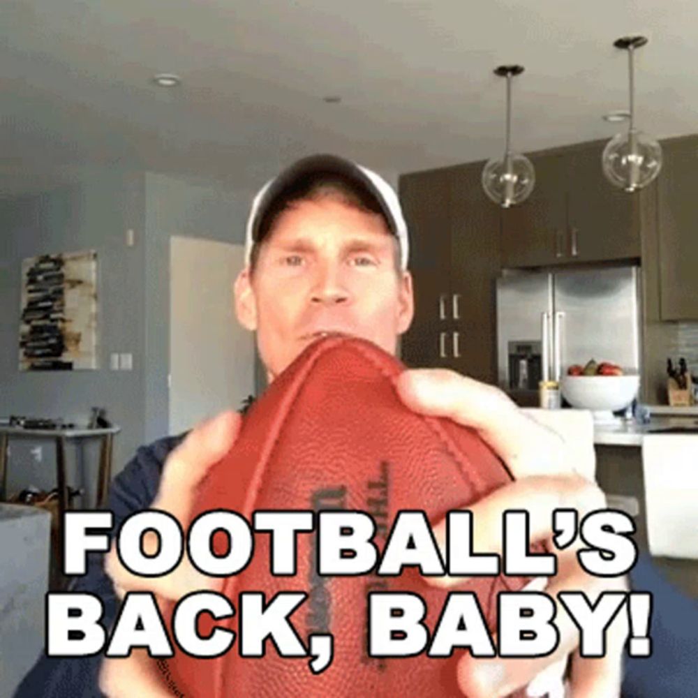 a man is holding a football with the words " football 's back baby " written on it