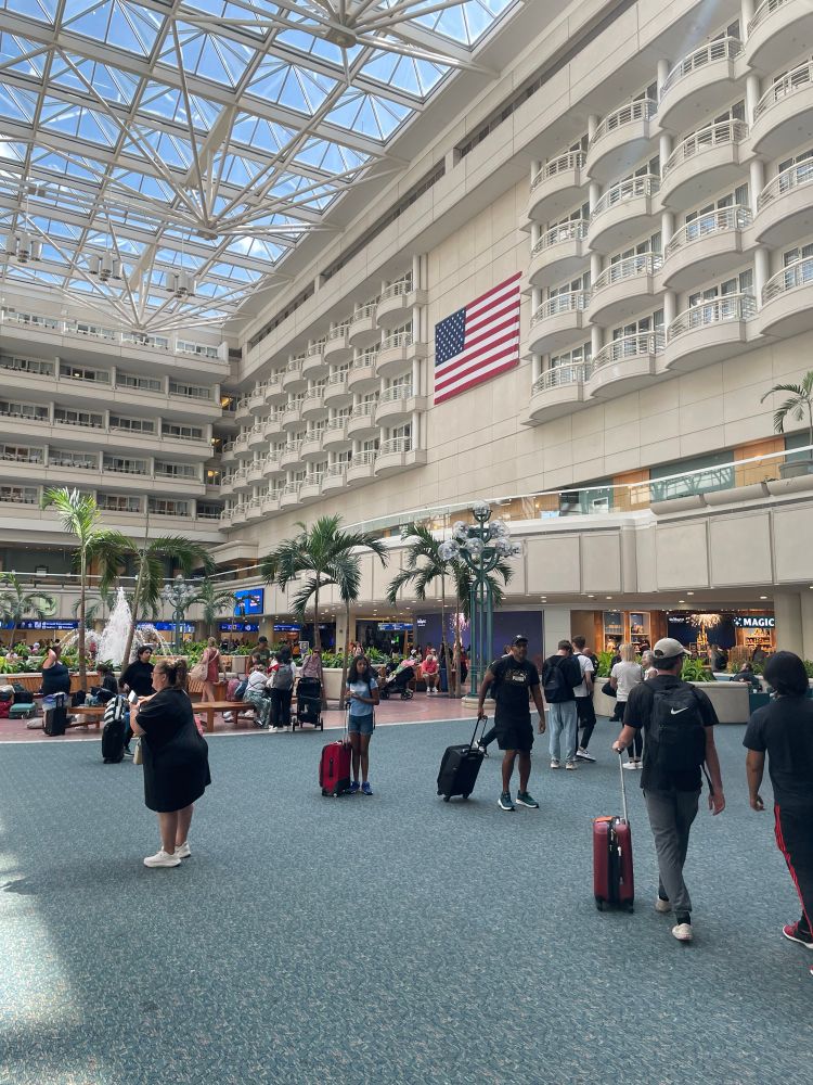 The terminal area at Orlando International Airport (MCO) featuring a water fountain fixture on the left and the US flag hanging on the wall on the right.